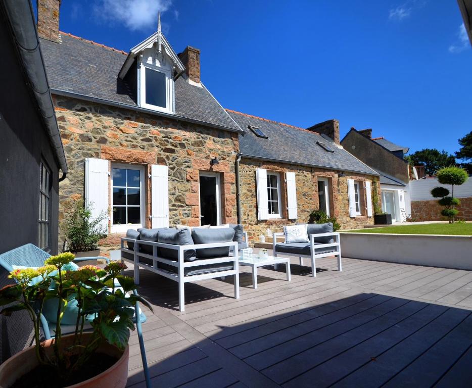 un patio avec des canapés et une table et un bâtiment dans l'établissement La Clarté-House, à Perros-Guirec