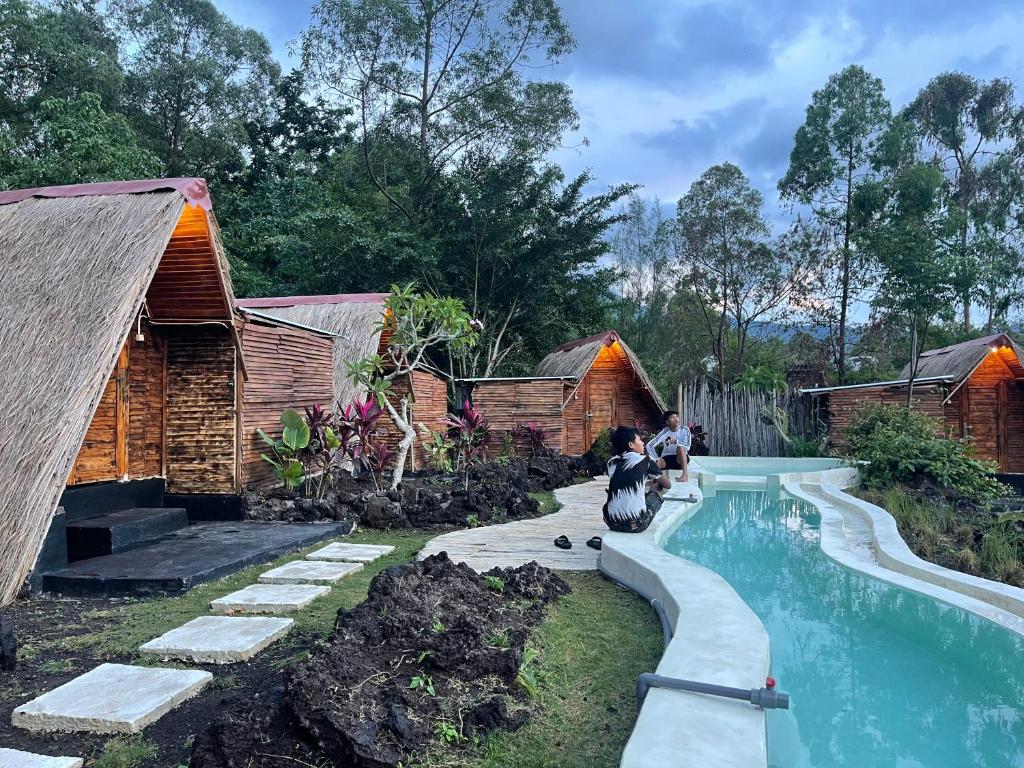 a woman sitting next to a swimming pool in a resort at Triangular house and hot spring in Kubupenlokan