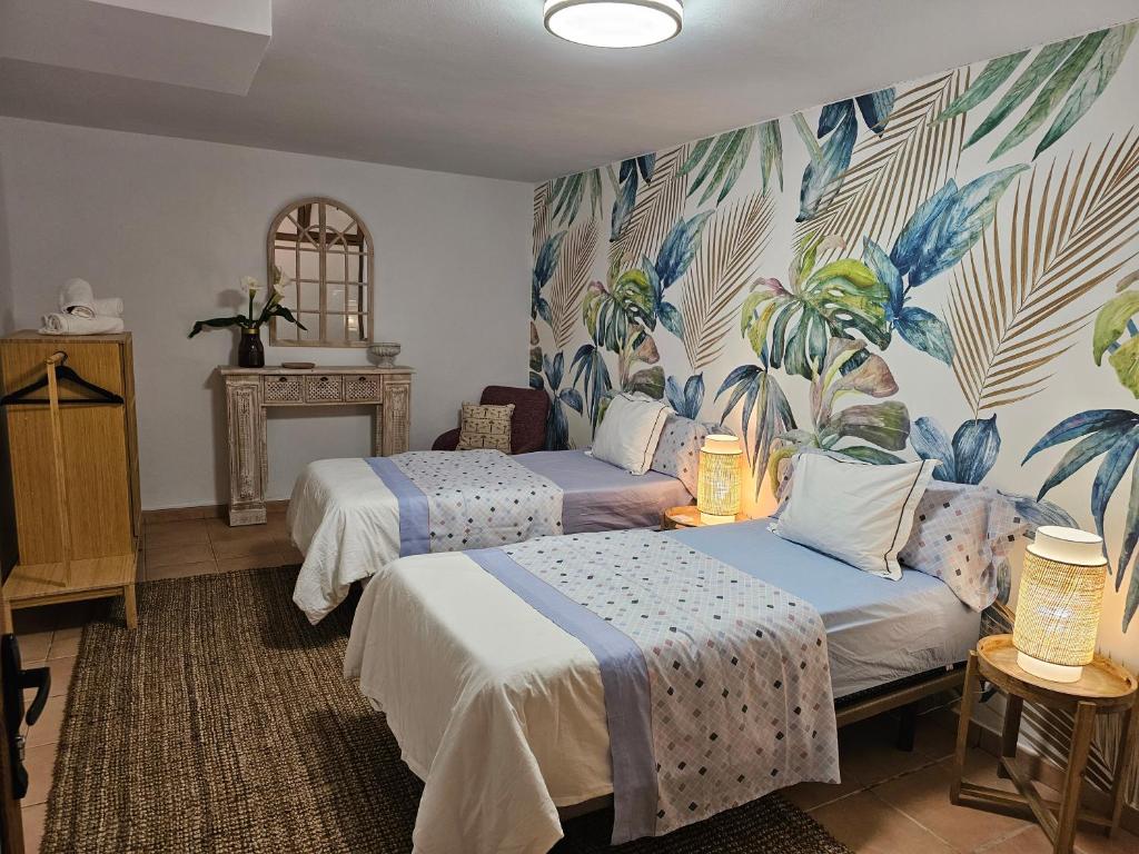 1 Schlafzimmer mit 2 Betten und einem Wandbild von Palmen in der Unterkunft Villa MOGAREN in Vega de San Mateo