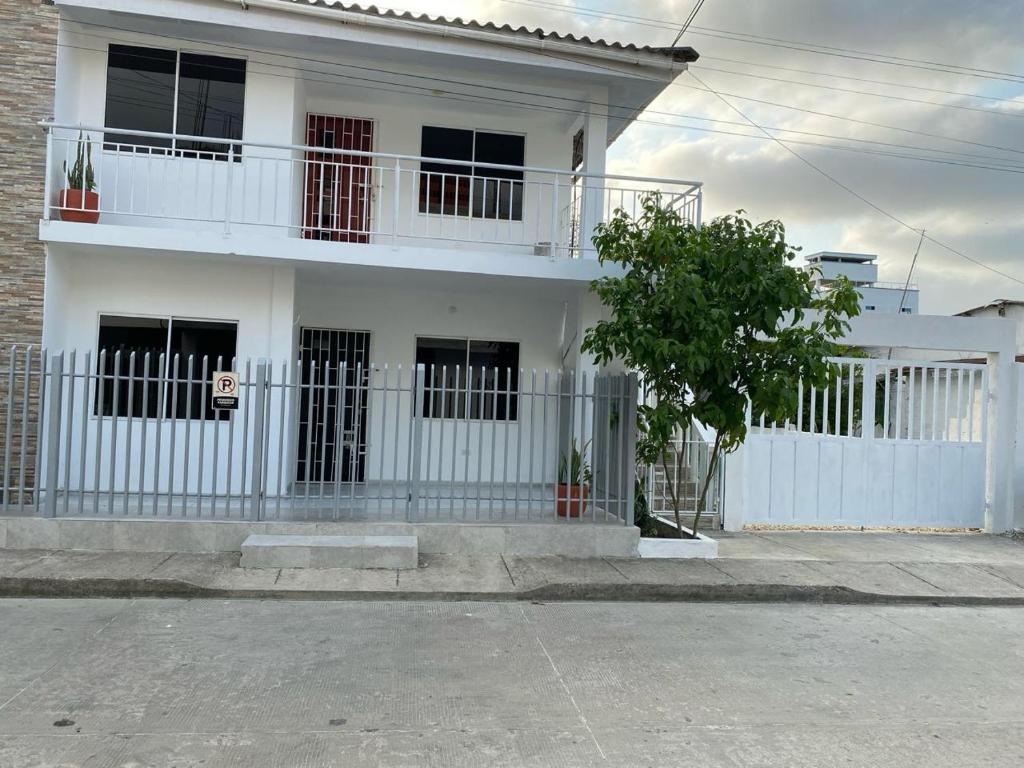 una casa blanca con una valla blanca y un árbol en Piantini Houses en Coveñas