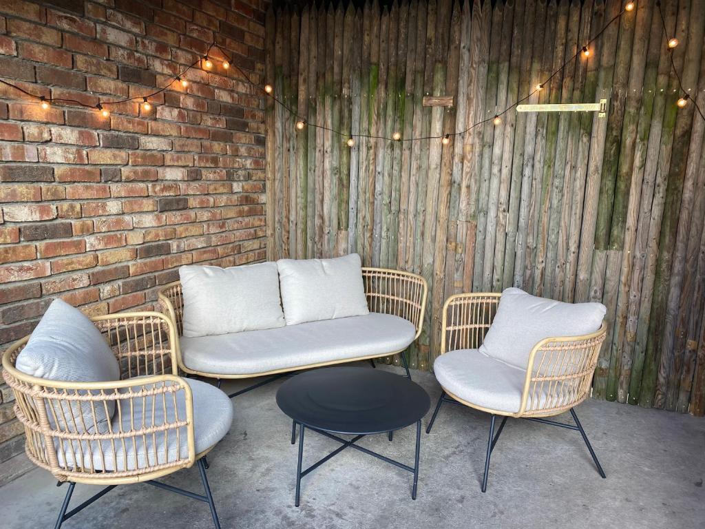 a patio with three chairs and a table and a brick wall at Privates & gemütliches Appartement inklusive Parkplatz in Drensteinfurt