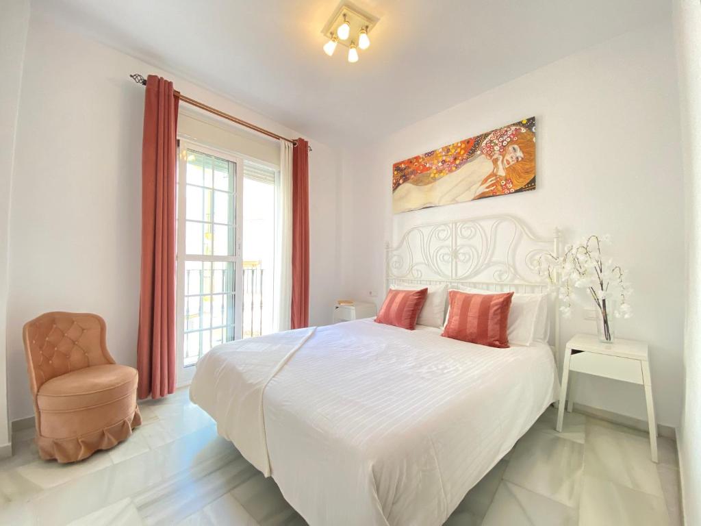 biała sypialnia z dużym łóżkiem i krzesłem w obiekcie La Pimentera Centro Histórico - Marbella w Marbelli