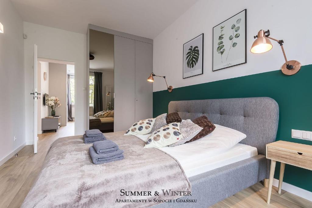 a bedroom with a bed and a green accent wall at Family Luxury Green Apartment 1-6, 2 sypialnie i studio, 52 m2 in Gdańsk