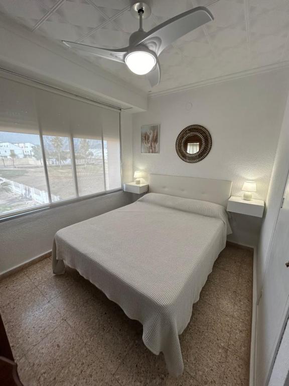 een witte slaapkamer met een bed en een plafondventilator bij Almenara Beach in Almenara