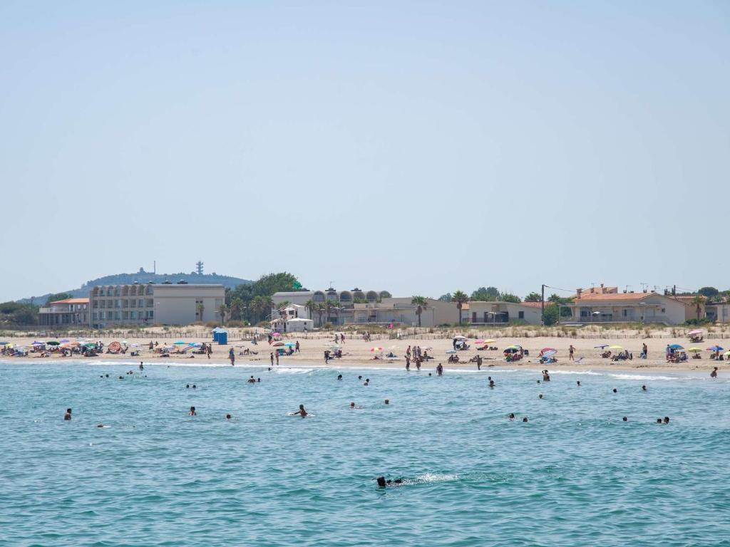 un groupe de personnes dans l'eau sur une plage dans l'établissement Appartement en Rez-de-Jardin Proche Plage avec Terrasse et Confort Moderne - FR-1-387-54, à Marseillan