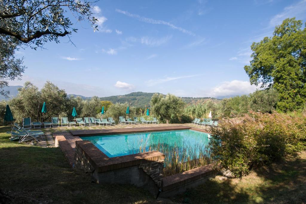 a swimming pool in a yard with chairs and umbrellas at Villa Sardini in Lucca