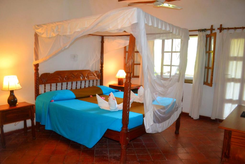 a bedroom with a canopy bed with blue sheets at Aquarius Club in Watamu