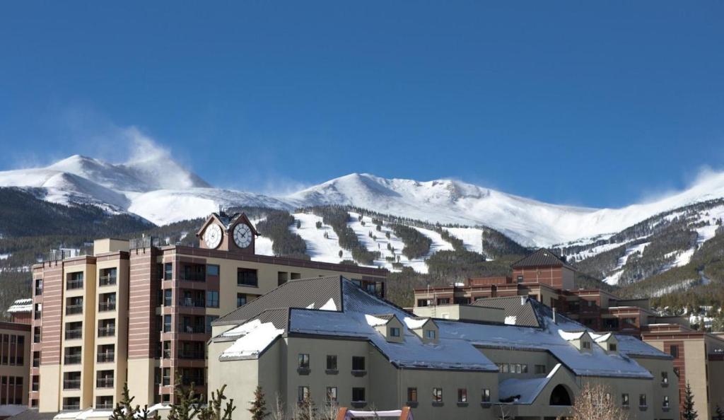 a building with a clock on top of it with snow covered mountains at Gravity Haus in Breckenridge