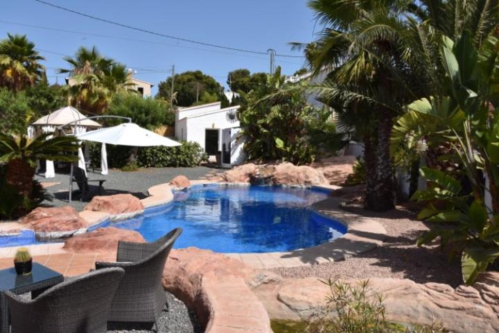 een zwembad in een tuin met stoelen en een parasol bij B&B Casa Sardonyx in Calpe