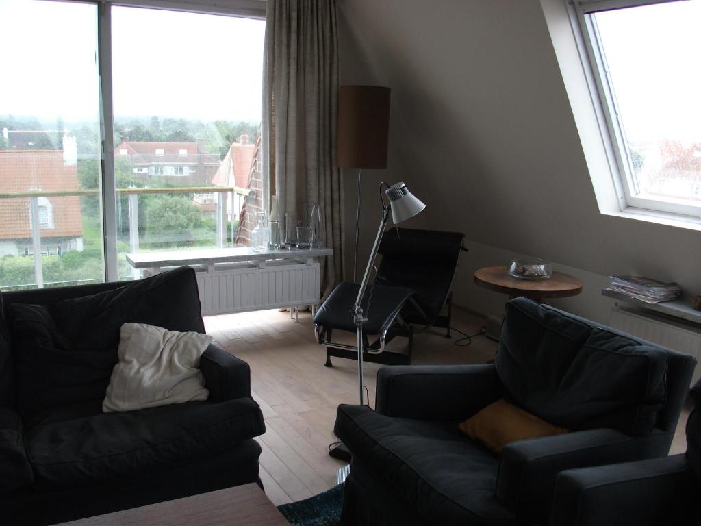 a living room with a couch and a table and window at Zoutezoute in Knokke-Heist