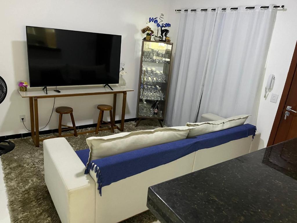 een woonkamer met een bank en een flatscreen-tv bij AP 2 Quartos 6 Pessoas Luxo 200mt Axé Moi in Porto Seguro