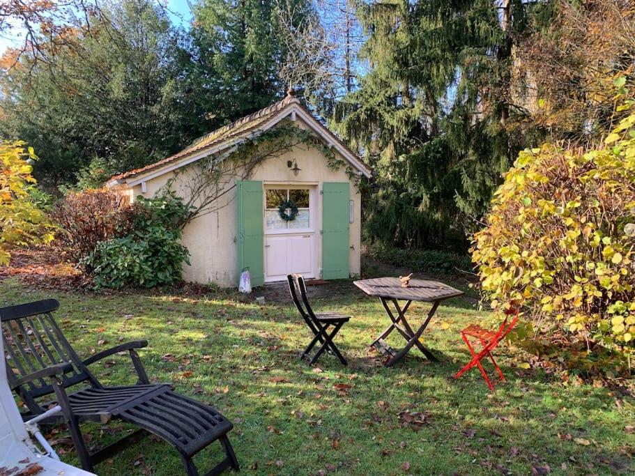 un pequeño cobertizo con una mesa y sillas en un patio en Maisonnette en clairière de forêt, en Gambais