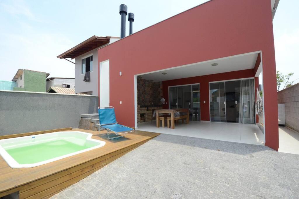 a red house with a hot tub on a patio at Casa Campeche 5 minutos, a Pé, da Praia in Florianópolis