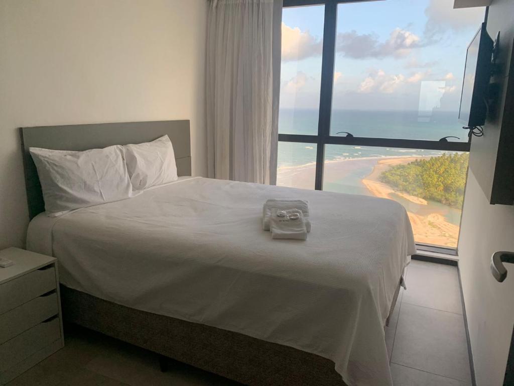a bedroom with a bed with a view of the beach at BARRA FLATS BY LOUI in Recife