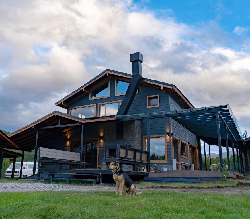 una casa con un perro parado frente a ella en La Finca Hostel de Montaña - Habitación Laguna en San Carlos de Bariloche