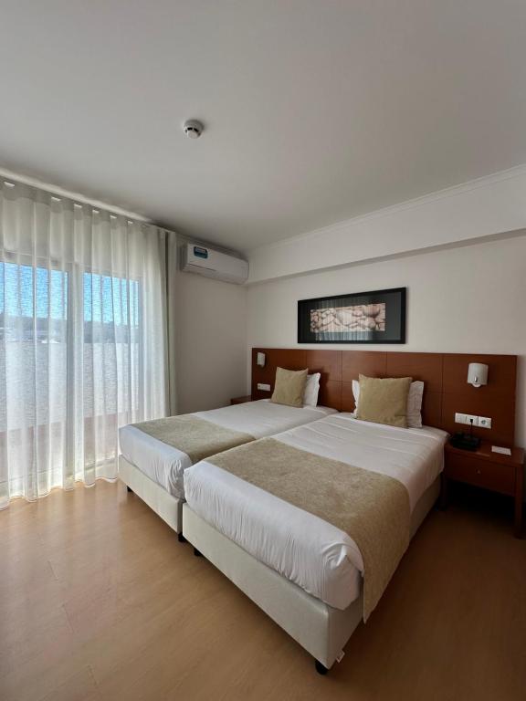 a bedroom with a large bed and a large window at Europeia Hotel in Caldas da Rainha