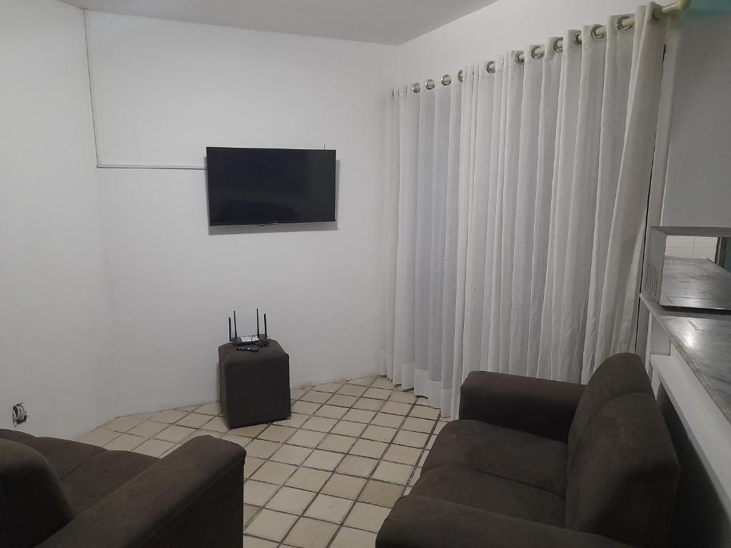 a living room with two couches and a flat screen tv at Dúplex mar de Pajuçara in Maceió