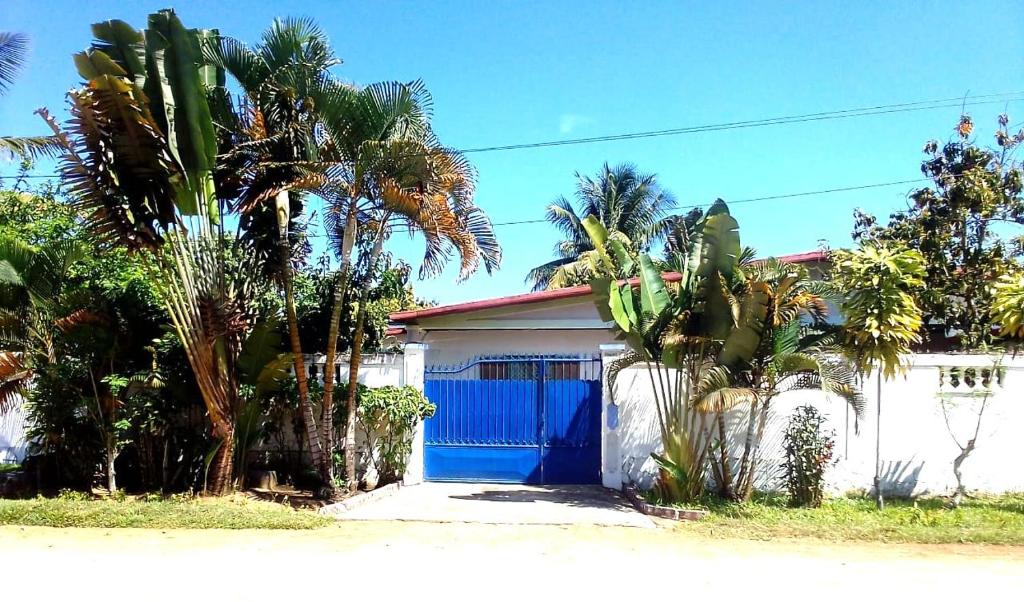 a house with a blue gate and palm trees at Maison d'hôtes Villa Mont du Pèlerin à Toamasina Madagascar in Toamasina