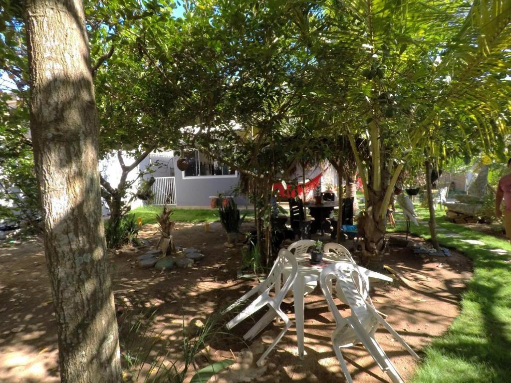 un banc blanc assis sous quelques arbres dans une cour dans l'établissement Casa Temporada em Praia Linda., à São Pedro da Aldeia