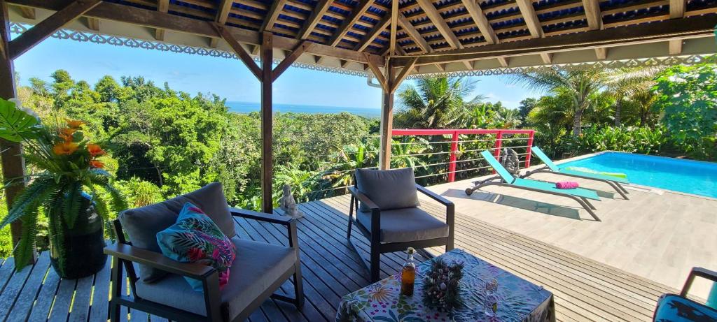 una terraza con sillas, una mesa y una piscina en Pipirite Chantant - Maison créole vue mer, en Sainte-Rose