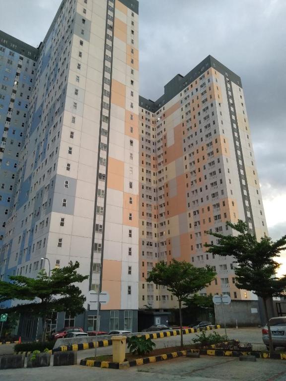 a tall building with trees in front of it at Urbantown Serpong Age Room in Dukuh
