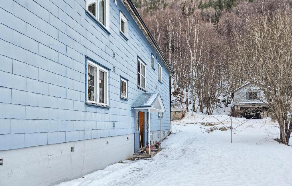 Cozy Apartment In Rjukan With House A Panoramic View في ريوكان: مبنى ازرق مع باب في الثلج