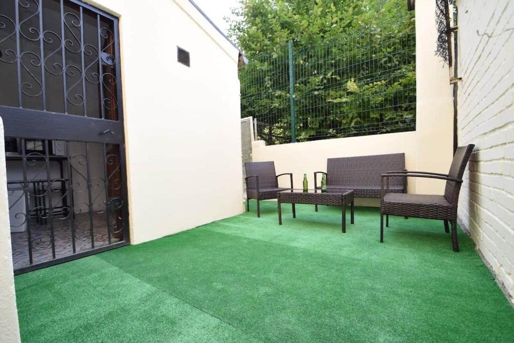 a patio with green flooring and chairs and a fence at Maison de ville haut de gamme En face du stade de France in Saint-Denis