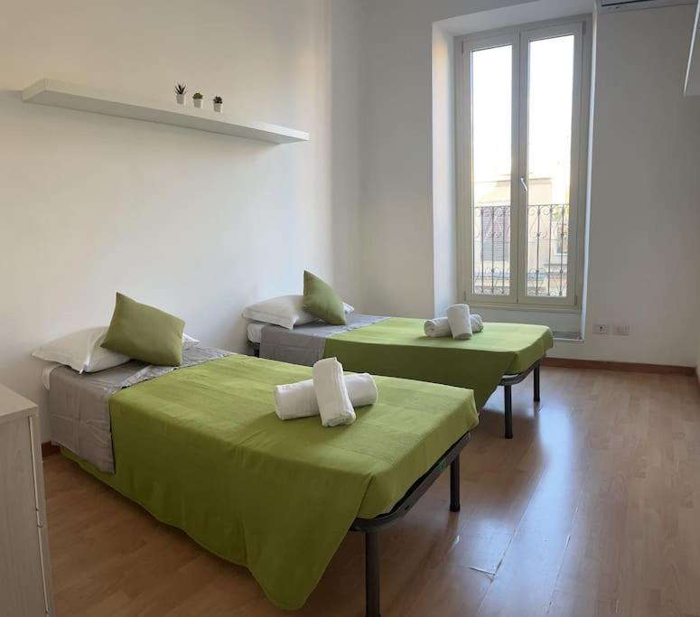 two beds in a room with green sheets at Rome Appartement in Rome