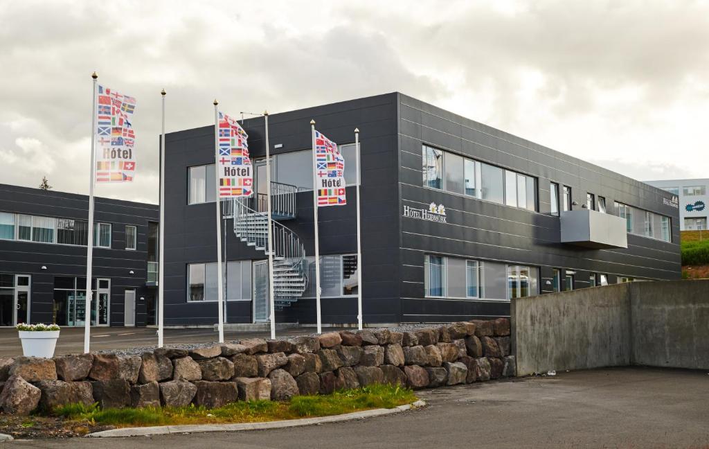 a black building with flags in front of it at Hótel Heiðmörk in Reykjavík