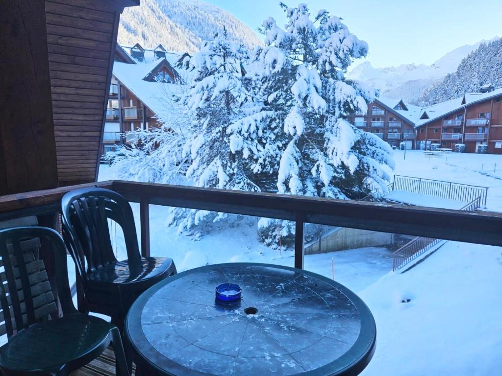 a table and chairs on a balcony with a snow covered tree at Aux pieds des pistes en plein soleil in Les Contamines-Montjoie