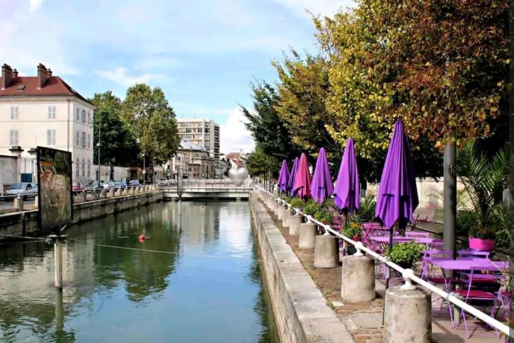 une rangée de parasols et de chaises violets à côté d'un canal dans l'établissement Appartement Les nuits de 3 Centre-ville, à Troyes