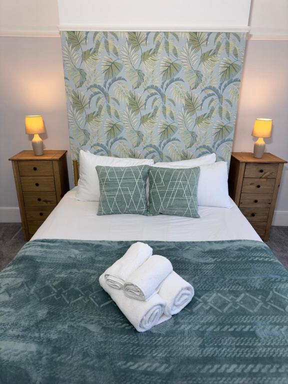 een slaapkamer met een bed met 2 handdoeken en 2 lampen bij Newly renovated, spacious East London home in Seven Kings