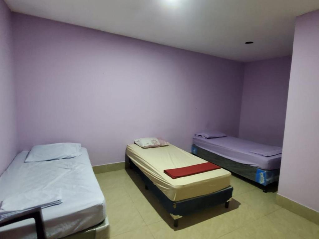 two beds in a room with purple walls at Hotel Putin in Jinotega