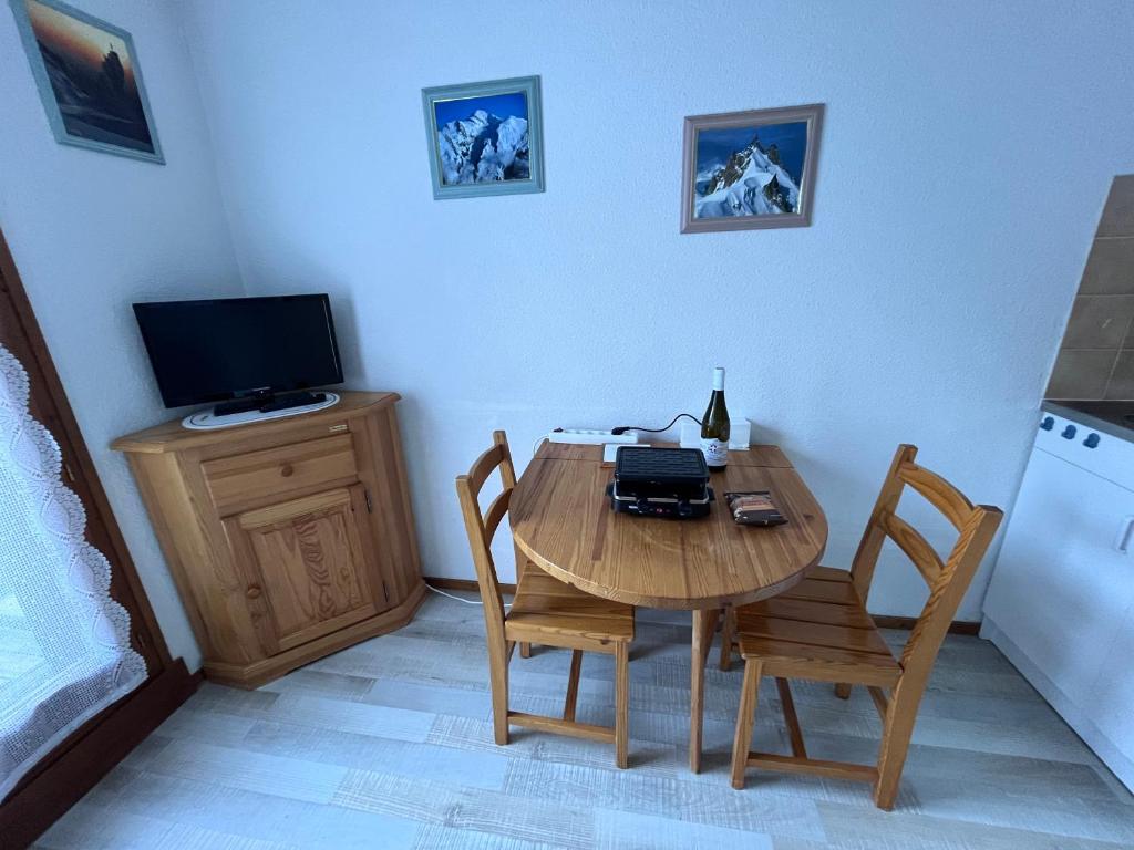 a kitchen with a wooden table with chairs and a television at Aux pieds des pistes en plein soleil in Les Contamines-Montjoie