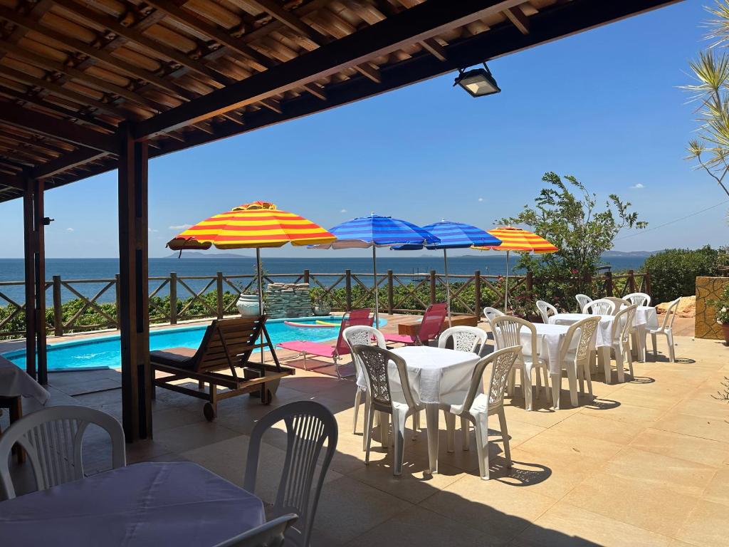 a row of tables and chairs with umbrellas and a pool at Chácara Pontal da Juacema - Sobradinho- Bahia in Sobradinho - Bahia