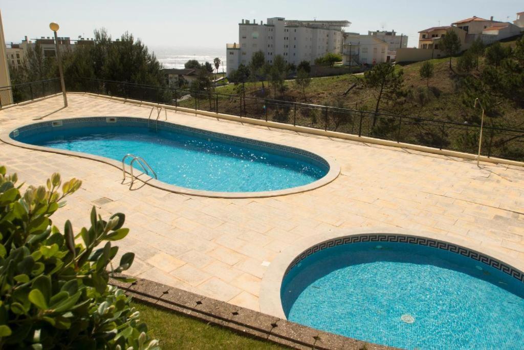 uma grande piscina com água azul em Quinta das Rosas - Beach and Mountain apartment em Buarcos