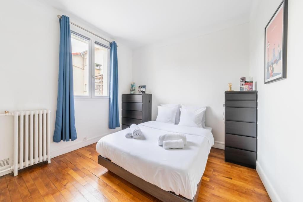 a bedroom with a white bed and blue curtains at Appartement Rousseau F2 in Montrouge