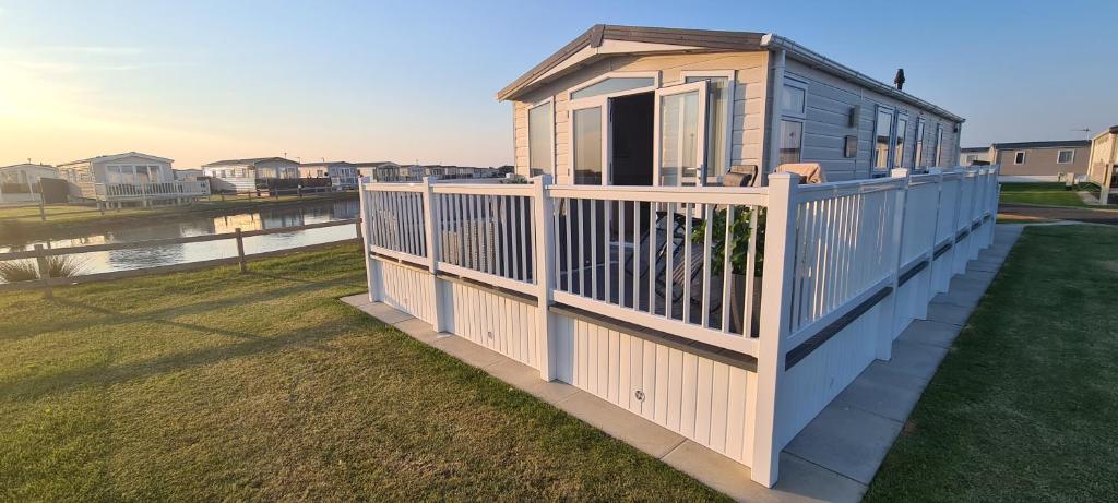 a small house with a fence on a deck at Golden Anchor Caravan Park, Europa Sequoia Private Static Caravan Hire on Wildflower Meadow in Chapel Saint Leonards