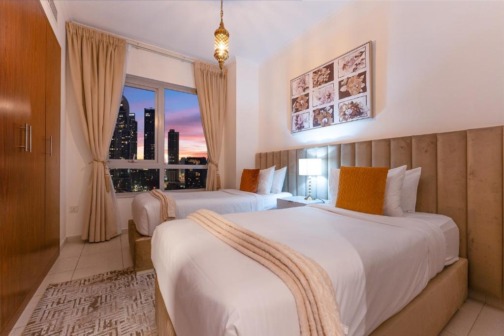 two beds in a hotel room with a window at Spectacular Burj & Fountain View - Luxurious 3 Bedrooms & Maids room - The Residences in Dubai