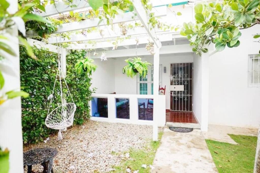 een wit huis met een tuin en een schommel bij Villa Vacacional, Playa Pascual in Santa Bárbara de Samaná