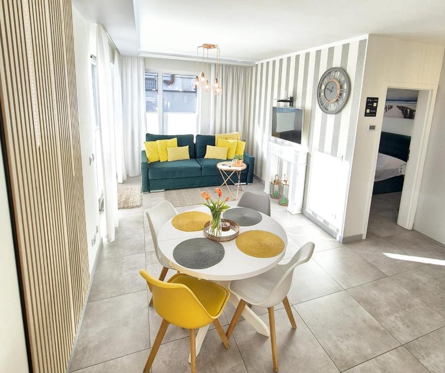 - un salon avec une table, des chaises et un canapé dans l'établissement Apartament Yellow Mielno, à Mielno