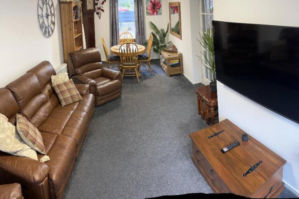 a living room with a leather couch and a table at No.46, comfortable 2 bedroom property in Rothes