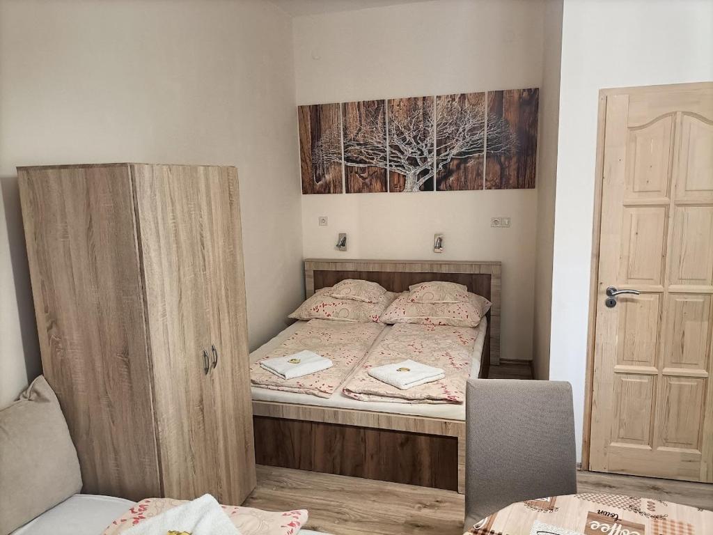 um pequeno quarto com uma cama e um armário de madeira em Elizabeth Apartman em Makó