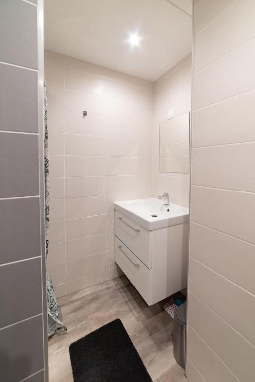 a white bathroom with a sink and a mirror at Studio Green Groupama Lyon , Eurexpo Aréna in Meyzieu
