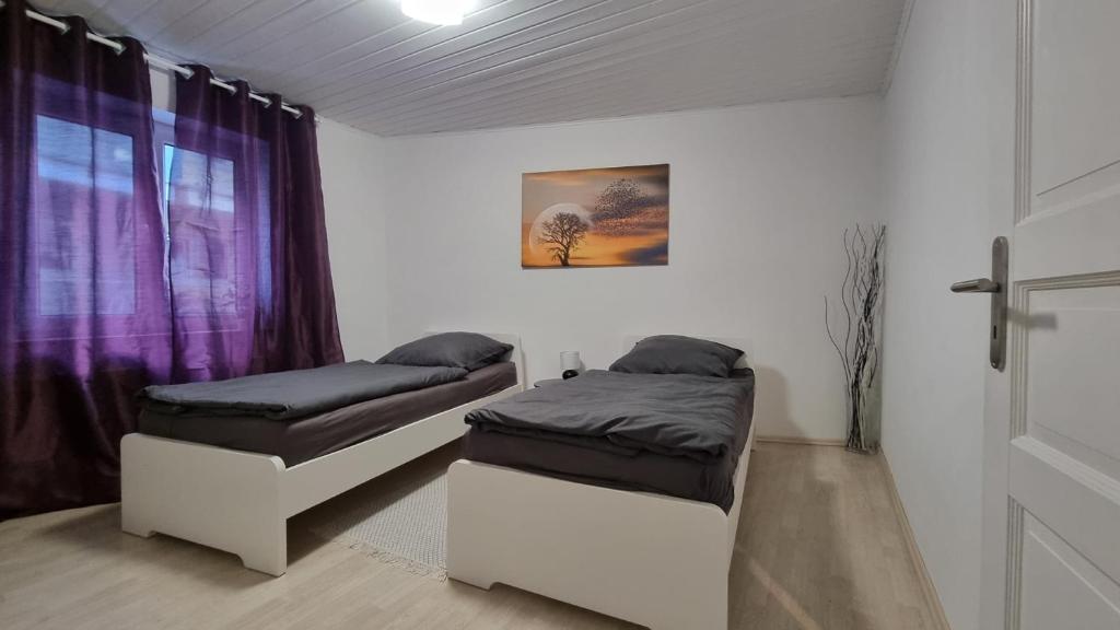 2 Betten in einem Zimmer mit lila Vorhängen in der Unterkunft 3 Zimmer 6 Betten Renoviert in Koblenz
