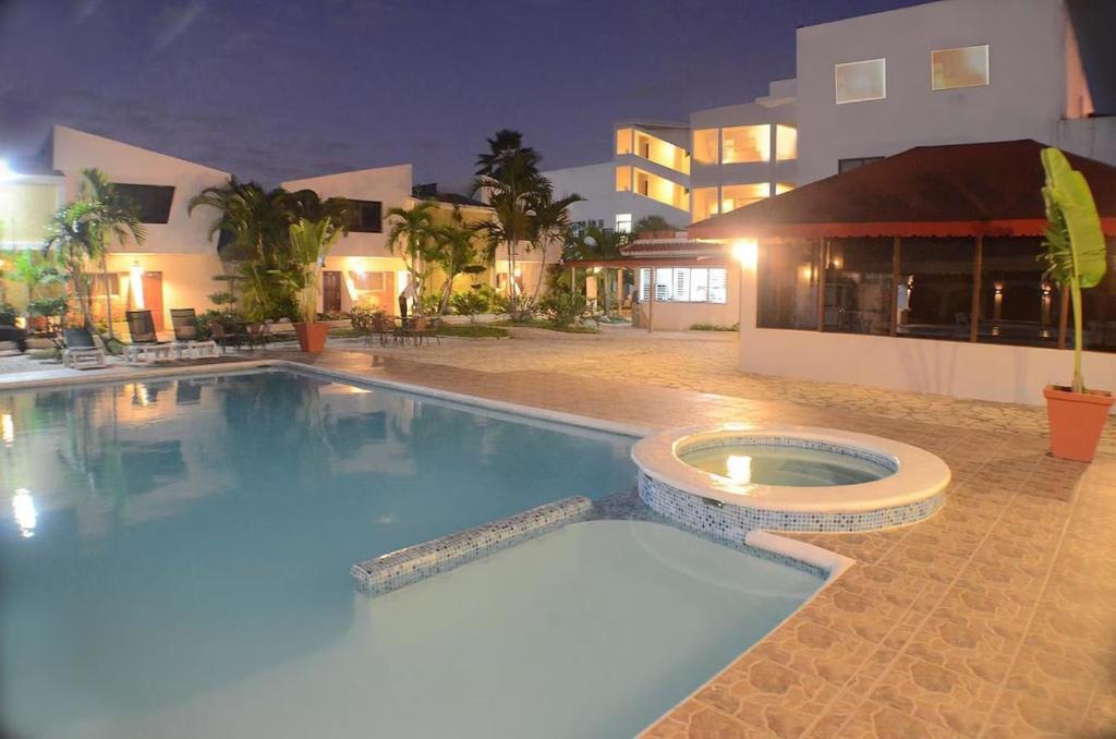 Hotel Tropicana Santo Domingo في La Viva: مسبح امام مبنى في الليل