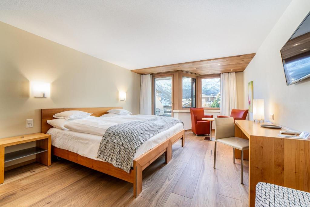 a hotel room with a bed and a desk and a desk at Hotel Allalin in Saas-Fee