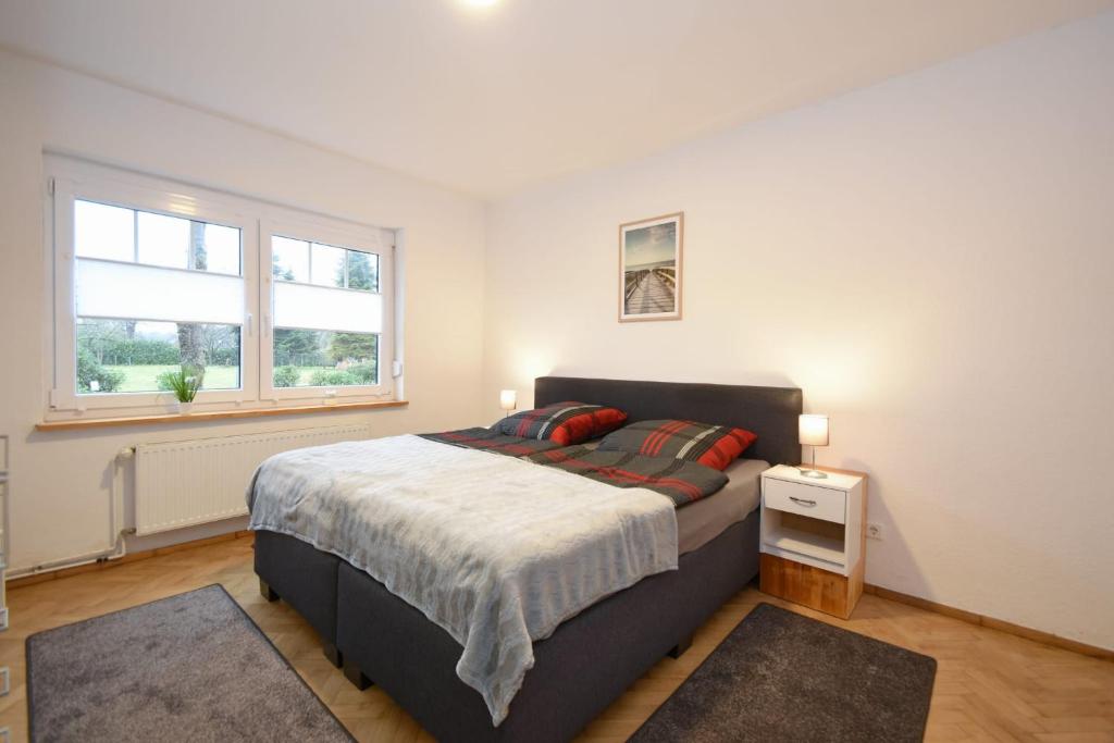 a bedroom with a large bed and two windows at Ferienhaus Auszeit in Westoverledingen