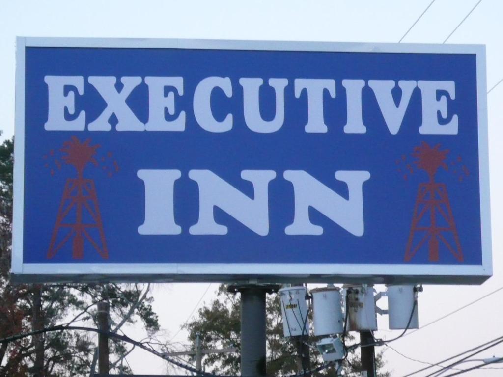 un cartello blu che dice "Locanda costosa" di Executive Inn Kilgore a Kilgore