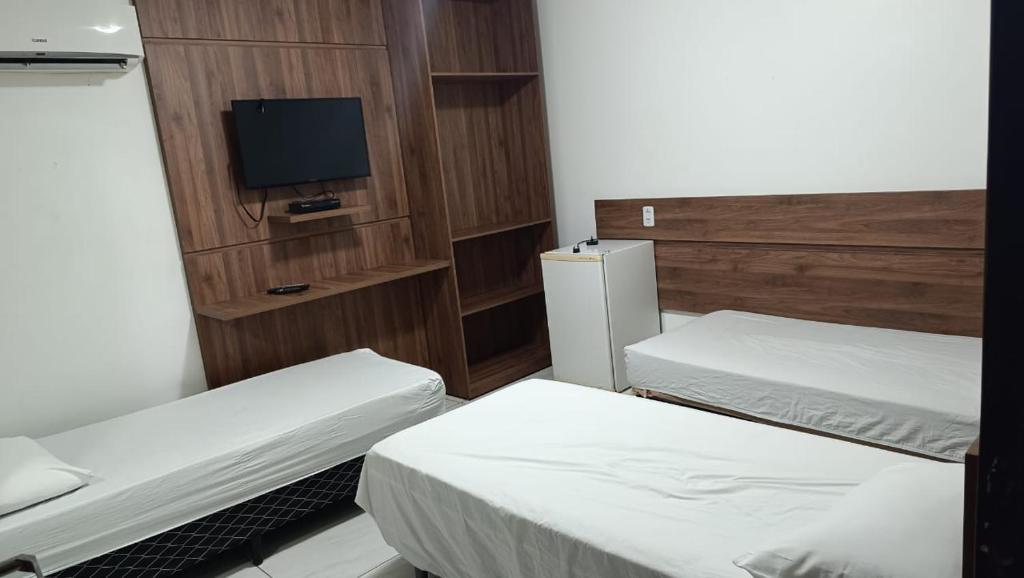 a small room with two beds and a television at Pousada Gaby in Salgueiro